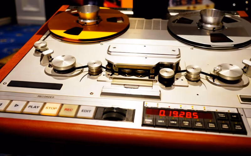 A vintage reel-to-reel tape recorder with transport controls and metering