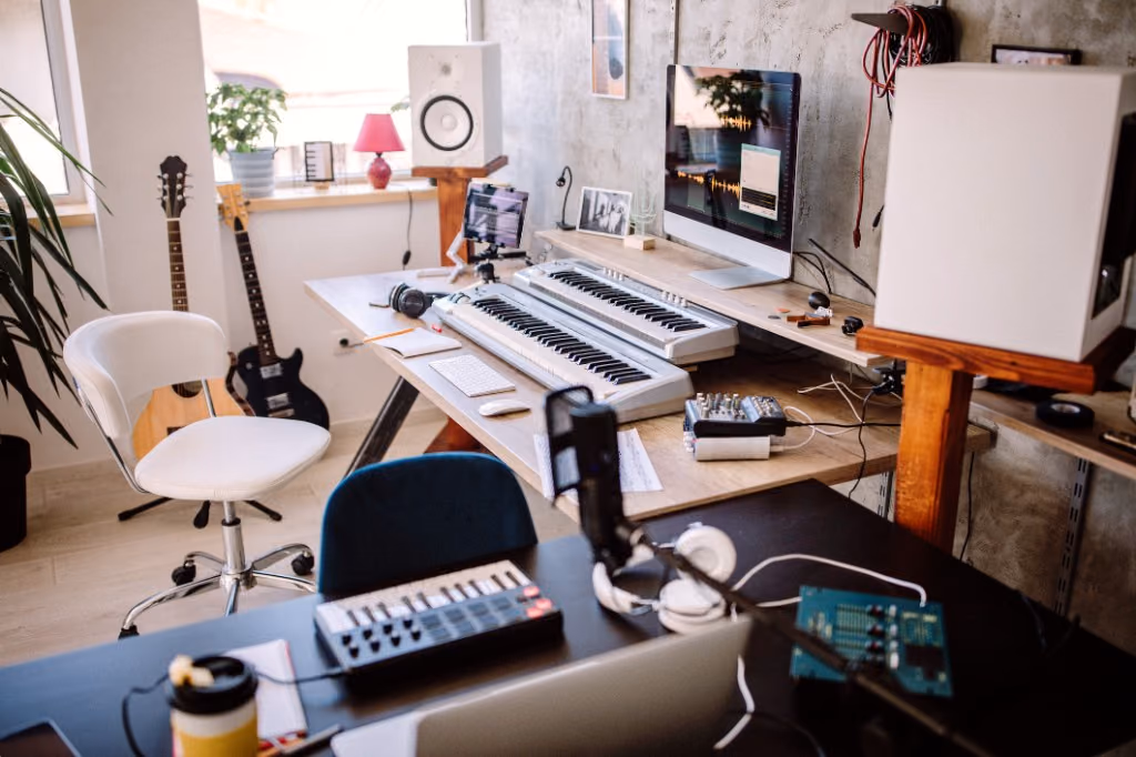 A home recording studio with a MIDI keyboard, guitars, studio monitors, and an audio interface